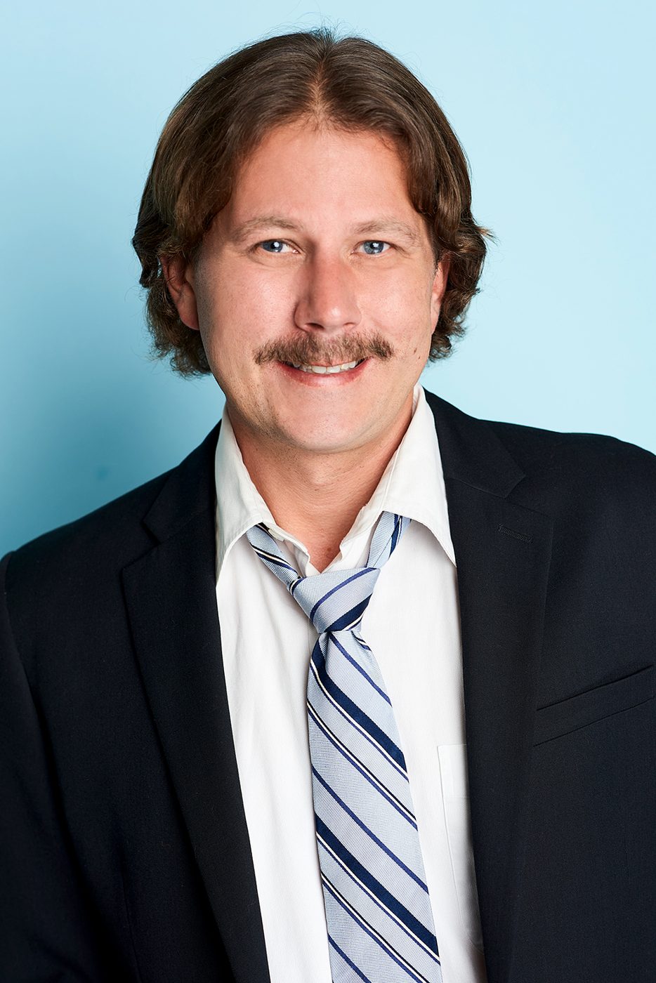 Joe Uhlarik headshot, suit and loose tie